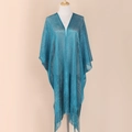 Detail of blue shimmering knit shawl featuring elegant fringe hem on a studio mannequin - Teal
