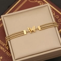 Elegante bracciale multistrato a farfalla dorata esposto su un portagioie in pelle beige - Bracciale