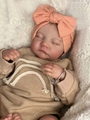 Detail of reborn doll wearing a bow headband and waffle knit top on soft white fleece - Standard Painted / Cloth Body