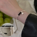Geflochtenes Silberarmband mit schwarzen Onyxperlen und Sternanhänger am Handgelenk - Schwarze Perle Lächeln Stern
