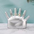 Silver hand-shaped jewelry stand showcasing resin rings on marble and leaf background - 6-Finger Silver