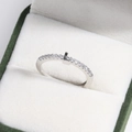 Macro shot of silver letter L ring with pavé diamonds in a dark green velvet box - Platinum L