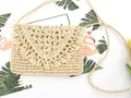 Detail of hand-woven straw crossbody bag with fringe trim on flap and slim braided strap - Beige