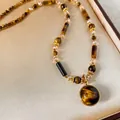Macro shot of Maillard-style tiger eye stone necklace with gold-plated bezel pendant - Tiger Eye Round Retro Adjustable Necklace (18K Gold Plated)