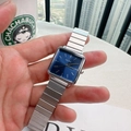 Macro view of square blue dial watch with silver stainless steel link strap held by hand - Silver/Blue