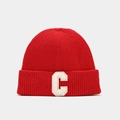 Detailed close-up of a red knitted beanie with a white plush letter C patch embroidery - Red