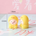 Nahaufnahme eines süßen Mini-Harzschweins im gelben Vogel-Hoodie, Größe 1,8 x 2,2 cm - Schwein im gelben Outfit