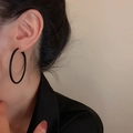 Detail view of large matte black hoop earrings worn on ear with minimalist style - Black Matte Hoop