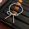 Detalle de pulsera de plata con lazo y eslabones cuadrados con borlas de cuentas en bandeja - Pulsera / Plateado