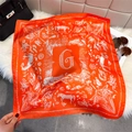 Detailed close-up of elegant orange silk square scarf with horse print and G pattern - Orange Red