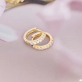 Close-up of 18K gold-plated earrings with clear zircon stones on soft petals - White