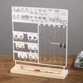 Multi-tier jewelry display stand with white metal hooks and a grooved wooden base - White