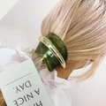 Détail d'une pince à cheveux en résine verte avec accents métalliques sur un magazine - Vert matcha