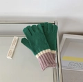 Soft knit gloves in green with pink and white cuffs displayed on a glass table - Contrast-Green