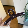 Macro di una grande clip per capelli viola scuro con molla dorata e finitura lucida - Rosso ciliegia