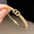 Macro-opname van in elkaar grijpende ringen op gouden armband met zirkoon pavé - In elkaar grijpende Dubbele Ring Kruisstijl (Jiaochai) / Goud