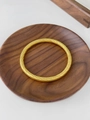 Dettaglio di un bracciale dorato con trama a spirale di alta qualità su piano in legno - A Quadri Oro