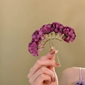 Detail van elegante paarse stoffen bloem haarspeld met een gouden metalen vorkbasis - Bloem haarstok / Paars