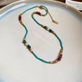 Dettaglio collana di perline colorate con perle in piatto ceramica stile boho - Blu-Rosso
