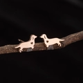 Polished rose gold dachshund stud earrings with heart cutout on dark wooden branch - Dachshund with Heart (782) / Rose Gold