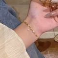 Elegant gold bracelet with zircon flower charms shown on wrist for styling - S689 Gold