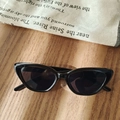 Classic black cat-eye kids sunglasses with dark lenses on a rustic wooden background - Black