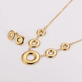 Détail d'un ensemble de bijoux cercles creux vintage avec motif grec doré sur fond blanc - Doré