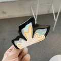 Detail of a butterfly acetate hair claw clip featuring blue marble patterns and orange trim - Butterfly