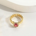 Macro detail of gold textured ring featuring a square red gemstone and cubic zirconia - Red Zircon