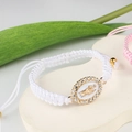 Close-up of white woven bracelet featuring an oval Virgin Mary charm with rhinestones - White