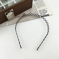 Close-up of black wavy metal headband with protective round tips on white surface - Double Wavy Headband / Black