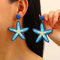Bohemian blue woven raffia starfish drop earrings shown on model for summer beach vacations - Golden Blue Starfish Style (10312)