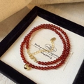 Detailed macro view of red natural stone beaded necklace with gold ball pendant in box - Red Bead Gold Pendant Style