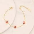 Golden stainless steel flower bracelet with colorful evil eye charms on ceramic tray - Red