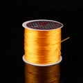 Elastic beaded crystal wire in bright yellow finish on white plastic spool with reflection - Orange