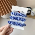 Three-piece set of blue satin scrunchies on a card display held by a person - 3 Piece Set / Blue