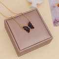 Nahaufnahme einer lila Glas-Schmetterlingskette mit Goldkette auf einer Geschenkbox - Dunkelviolett