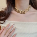 Nahaufnahme einer klobigen goldenen Gliederkette an einem Model in neutraler Kleidung - Halskette - Gold