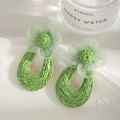 Detailed shot of green tulle flower earrings with hand-woven raffia teardrop rings - Green