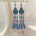 Macro shot of Bohemian tassel earrings with colorful beads and bronze metal alloy details - Teal and Red Tassel Style