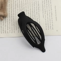 Classic black oval duckbill hair clip with hollow design on a vintage book page - Matte Black