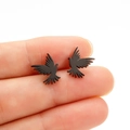 Macro de pendientes de pájaro en negro mate sostenidos por la mano para mostrar tamaño - Negro