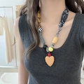 Detailopname van boho stoffen ketting met houten kralen en een gele hart hanger - Kleurrijke Hart Hanger Stijl