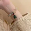 Detail eines Perlenarmbands mit grünen Jade-Perlen und rotem Glücksanhänger am Handgelenk - Weißes Lotus-Jade-Armband (1# Armband - Weiß - Lotus)
