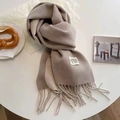Beige soft knit scarf with tassels and label on white table for a cozy winter vibe - Light Khaki