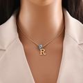Detail of gold necklace featuring letter R pendant and small blue bead on model - Letter R (N1339)