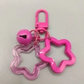 Pink acrylic hollow star keychain with matching bell and chain on grey background - Rose Red