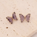 Macro shot of purple butterfly earrings with zircon stones and golden metal claws - Deep purple