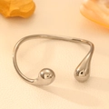Detailed view of polished stainless steel open bangle with bulbous drop ends on leather - Steel Color (Silver)