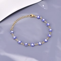 Dettaglio macro del bracciale occhio greco dorato con perline blu nazar e moschettone - Blu